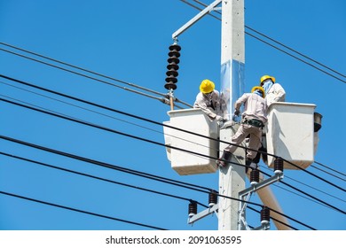 Group of Male Engineer or Electrician working on Crane Bucket over Electrical Pole with Hardhat and Safety tools as Maintenance Services for Power industry line or Technology Communication Cable.