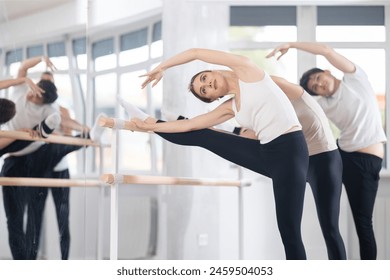 Group of male and female dancers perform stretches at barre in dance class - Powered by Shutterstock