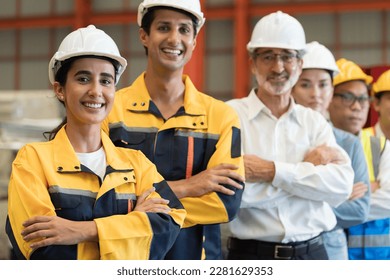 Group of male and female factory workers standing together with crossed arms and smiling in industry factory, wearing safety uniform and helmet. Factory workers working in factory - Powered by Shutterstock