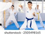 Group of male and female karateists practicing karate techniques in gym..