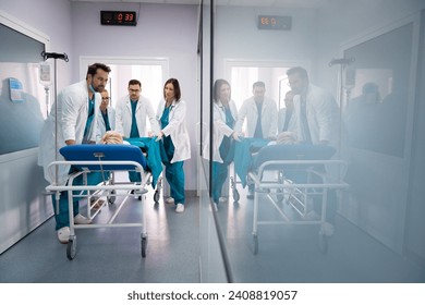 Group of male and female surgeons and doctors pushing unconscious patient on the bed into urgent surgery at hospital. Medical team in a hurry to save patients life. - Powered by Shutterstock