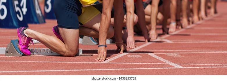 Gruppe männlicher Gleissportler auf Startblöcken.Hands auf der Startlinie.Athleten auf der Sprint-Startlinie in Gleis- und Feldbahn