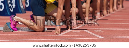 Group of male track athletes on starting blocks.Hands on the starting line.Athletes at the sprint start line in track and field