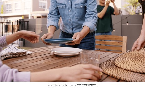 Group of man woman asia people fun joy prepare set dine table plate glass cutlery in cozy party host event at home front yard patio. Young adult child friend enjoy happy warm time picnic lunch meal. - Powered by Shutterstock