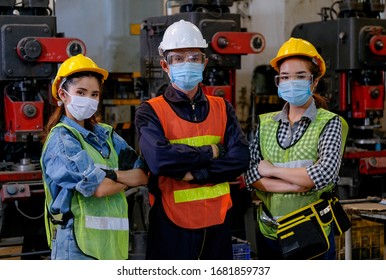 Gruppen von Arbeitern mit Maske stehen mit selbstbewusstem Handeln in der Fabrik und verschiedenen Maschinen als Hintergrund.