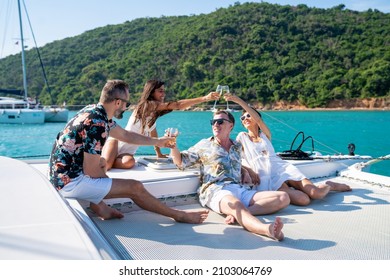 Group Of Man And Woman Friend Enjoy Party Drinking Champagne With Talking Together While Catamaran Boat Sailing In Summer Sunny Day. Male And Female Relax Outdoor Lifestyle On Tropical Travel Vacation