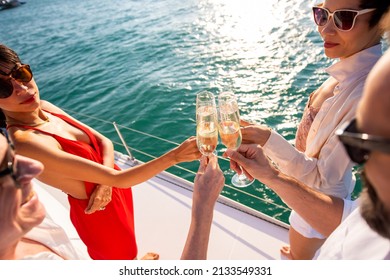 Group Of Man And Woman Friends Enjoy Party Drinking Champagne With Talking Together While Catamaran Boat Sailing At Summer Sunset. Male And Female Relax Outdoor Lifestyle On Tropical Travel Vacation