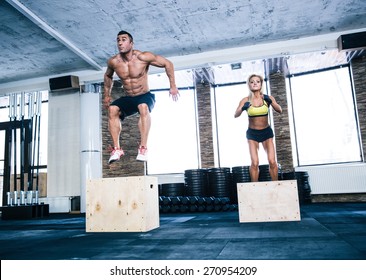 Group of man and woman jumping on fit box at gym
