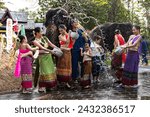 Group of man, women and children in traditional Thai costumes having fun splashing water to each other on Song kran festival in elephant camp, Chiangmai Thailand
