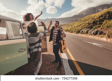 Group Of Man And Women On Road Trip Standing By The Van And Giving High Five. Cheerful Friends Enjoying Themselves On A Vacation.