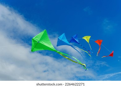 Group of many beautiful color kites fly on the string over blue sky with clouds - Powered by Shutterstock