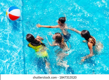 Group Of Many Kids Jump After Inflatable Ball, Play In Swimming Pool, View From Above