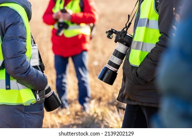 Group Of Many People Watching Planes Landing And Take Off Airport Runway Field Planespotting Conference Warm Morning Time. Planespotters In Safety Vest Waiting Aicraft Arrival Approaching Departure