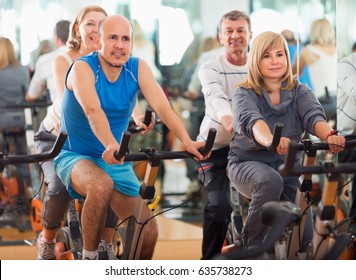 Group of mature active people cycling in a gym