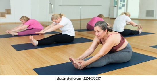 Group Of Mature Active Women Practicing Yoga, Making Together Stretching Asanas