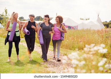 Group Of Mature Female Friends On Outdoor Yoga Retreat Walking Along Path Through Campsite