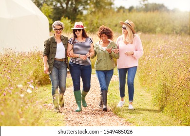 Group Of Mature Female Friends Walking Along Path Through Yurt Campsite