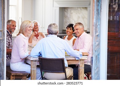 Group Of Mature Friends Enjoying Meal At Home Together