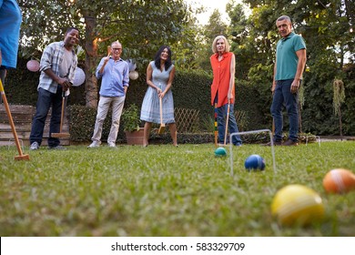 Group Of Mature Friends Playing Croquet In Backyard Together