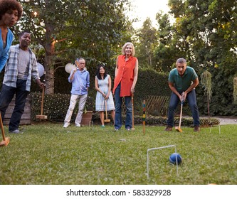 Group Of Mature Friends Playing Croquet In Backyard Together