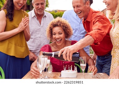 Group Of Mature Friends At Surprise Birthday Party For Woman In Garden With Cake And Champagne - Powered by Shutterstock