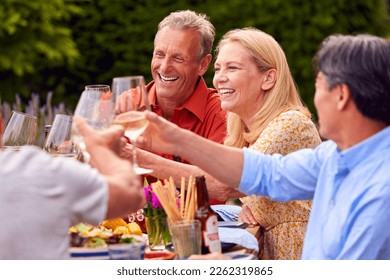 Group Of Mature Friends Talking And Making A Toast With Wine At Summer Party In Garden At Home - Powered by Shutterstock