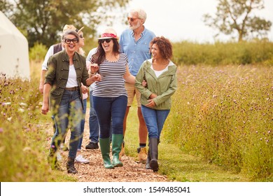 Group Of Mature Friends Walking Along Path Through Yurt Campsite