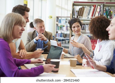 Group Of Mature Students Collaborating On Project In Library