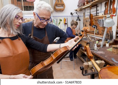 group of mature violin maker in pose while testing the violins in his laboratory - Powered by Shutterstock