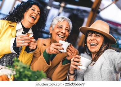 Group of mature women having  fun at the café bar enjoying breakfast drinking coffee- Three senior female  taking selfie with smart phone outdoors at cafeteria dehor-Life style concept  - Powered by Shutterstock