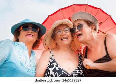 Group mature women wearing beach hats and smiling while standing on a tropical beach. Older ladies have fun in outdoor leisure activity in holiday vacation summer lifestyle. Elderly friends lifestyle - Powered by Shutterstock