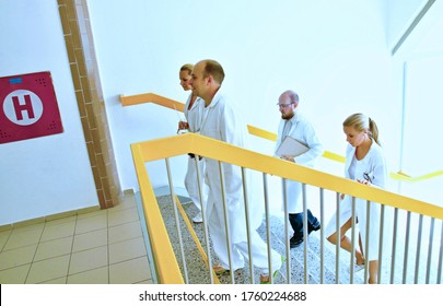 Group Of Medical Doctors And Specialists With Protective Coats Going The Hospital Corridor Up The Stairs. Doctor Specialist, Surgeons, Science, Research, Pharmacy, Colleagues And Teamwork Concept.