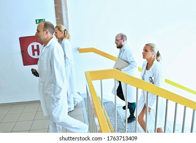 Group Of Medical Doctors And Specialists With Protective Coats Going The Hospital Corridor Up The Stairs. Doctor Specialist, Surgeons, Science, Research, Pharmacy, Colleagues And Teamwork Concept.