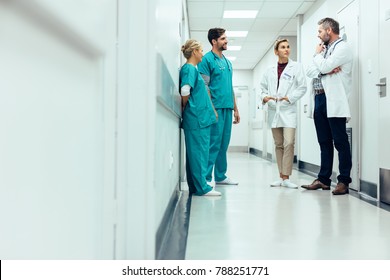 Gruppe von medizinischem Personal, das in der Klinik-Halle diskutiert. Angehörige der Gesundheitsberufe, die im Krankenhauskorridor diskutieren.