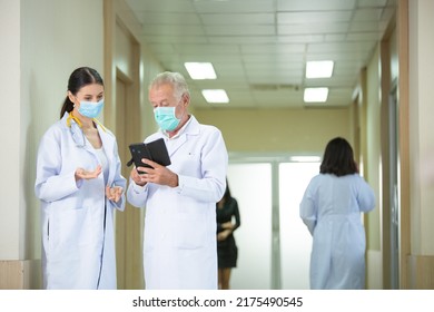 Group Of Medical Staff In The Hospital Hallway. Doctors Wearing Protective Mask Discussing And Consulting Patient Case. 
