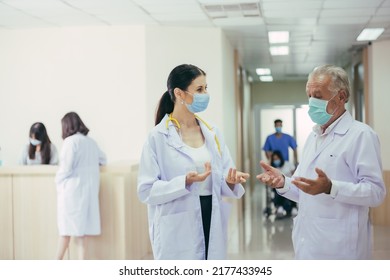 Group Of Medical Staff In The Hospital Hallway. Doctors Wearing Protective Mask Discussing And Consulting Patient Case. 