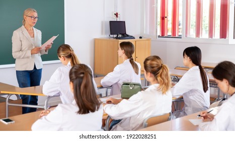 Group Of Medical Students Attentively Listening To Lecture Of Female Teacher In Classroom