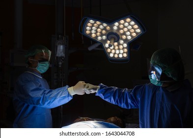 group medical team surgeon doctor joining hands and performing surgery at work for rescue patient in operation room at hospital, medical technology, health care cancer disease treatment concept - Powered by Shutterstock