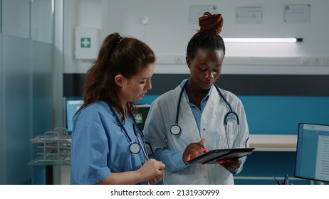 Group Of Medical Workers Using Tablet For Consultation And Patient Healthcare In Doctors Office. Team Of Doctor And Nurse With Stethoscope Working With Touch Screen Device For Practice.