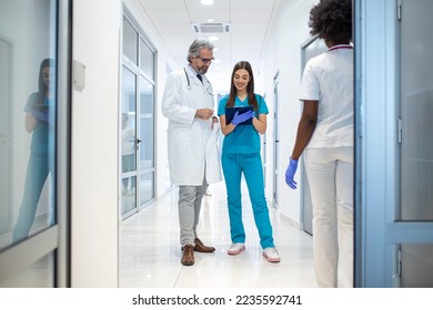 Group of medics with clipboard discussing along hospital corridor. Doctor and nurse briefing medical report - Powered by Shutterstock