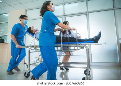 a group of medics or doctors carrying male patient on hospital gurney to emergency or operation room, urgent caseon  gurney being pushed at speed through a hospital. - Shutterstock ID 2007663266