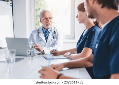 Group of medics during briefing in clinic boardroom. Medical workers team working together, explaining medical cases in hospital, treatment, drugs prescription - Powered by Shutterstock