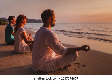 group meditation, people practicing yoga on the beach, relaxation and breathing excercises - Powered by Shutterstock