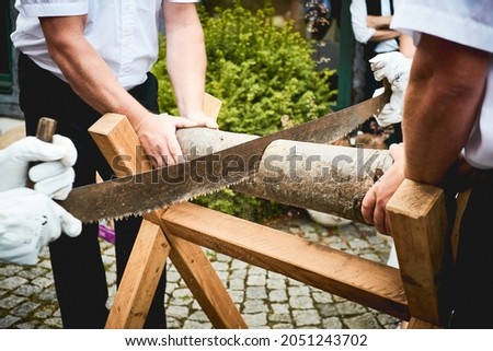 A group of men cutting a log using a two man crosscut handsaw