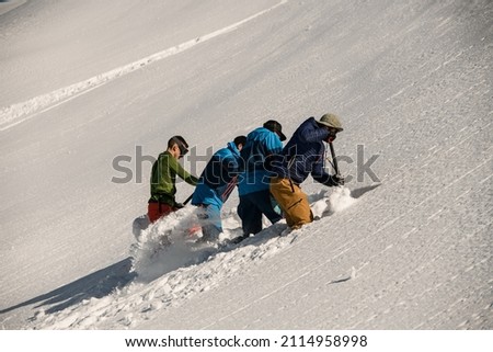 group of men are digging snow and checking the mountain for avalanche safety. Making schurf. Freeride concept
