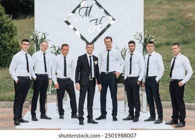 A group of men are dressed in suits and ties, posing for a photo in front of a white wall. Scene is formal and elegant, as the men are dressed in business attire and are standing in a line - Powered by Shutterstock