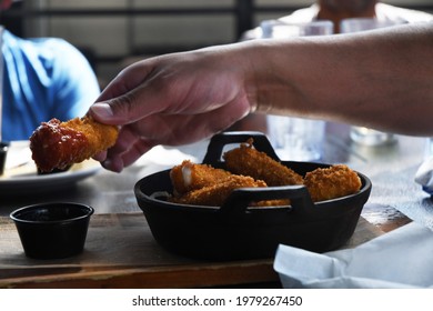 A Group Of Men Enjoy Buffalo Wings And Mozzarella Sticks At A Sports Bar.