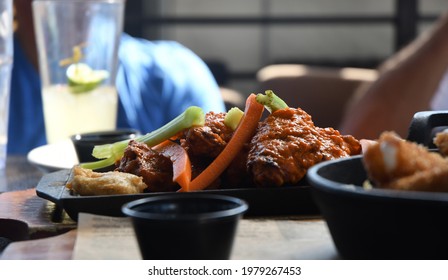 A Group Of Men Enjoy Buffalo Wings And Mozzarella Sticks At A Sports Bar.