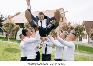 A group of men are playing with each other, one man is jumping and the others are lifting him. Scene is playful and fun - Powered by Shutterstock