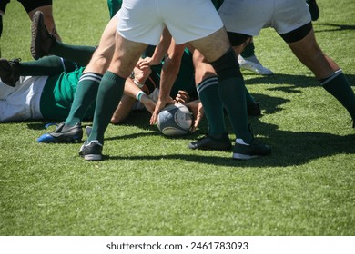 Group of men playing rugby on grass field, tackling and passing ball in action-packed match. - Powered by Shutterstock